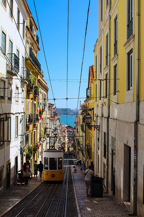 Straßenbahn Lissabon mit Blick auf eine Gasse und das Meer, Urlaub in Lissabon