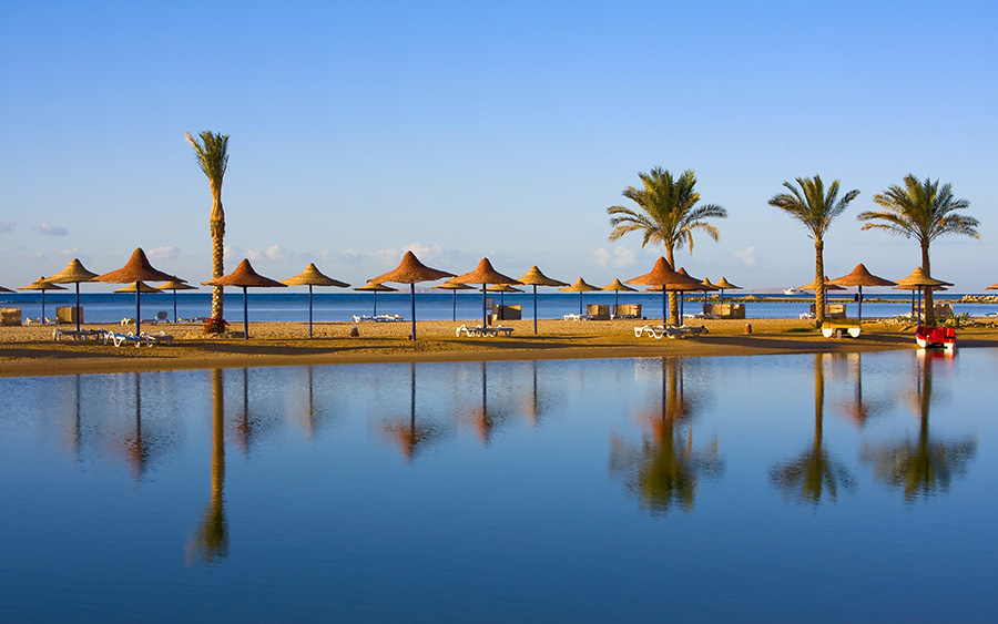 Strand in Hurghada, Ägypten, mit Stroh-Sonnenschirmen und Meer, Urlaub in Ägypten