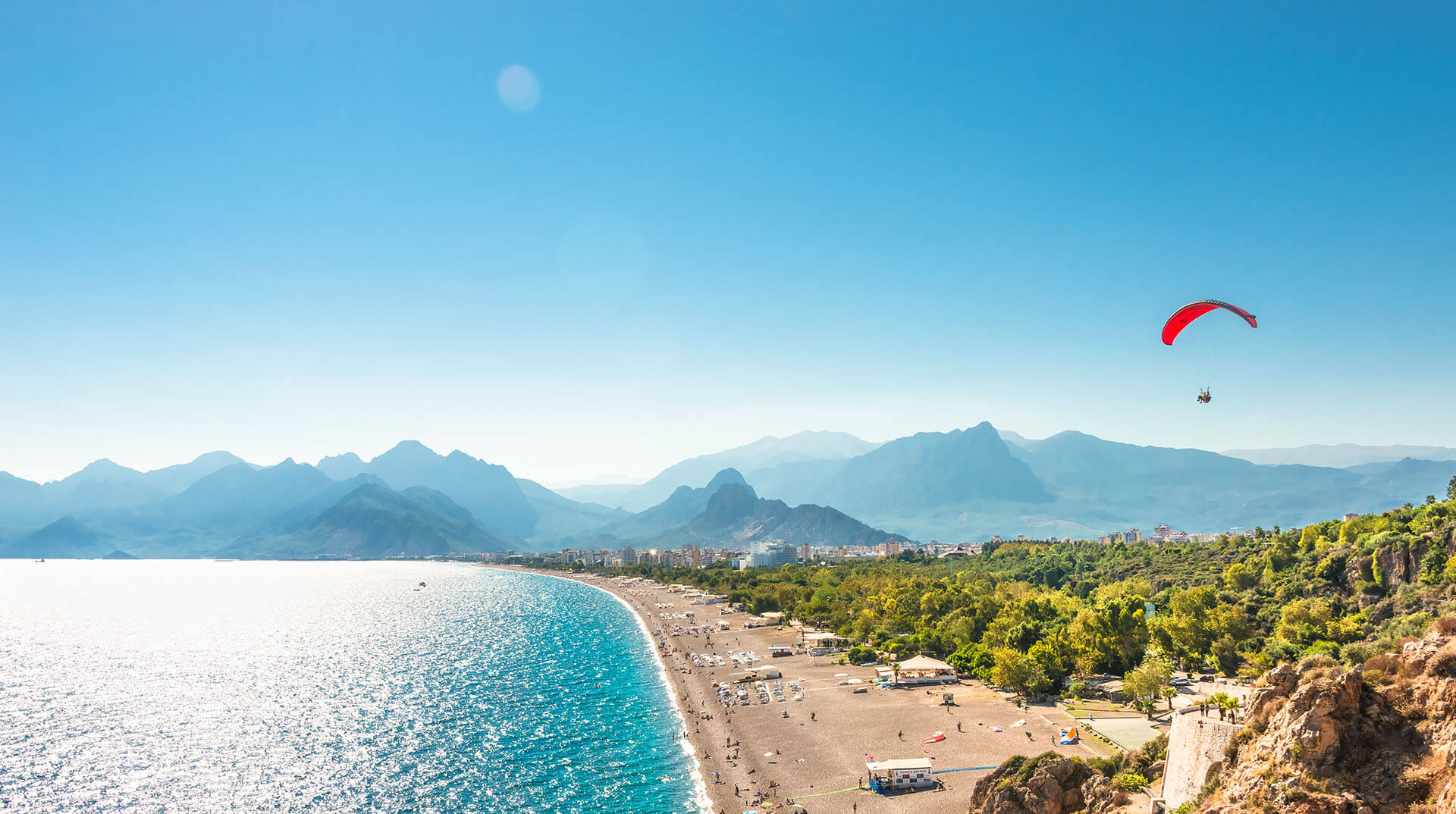 Panoramablick auf Antalya und Mittelmeerküste und Strand mit Einem Gleitschirm, Antalya, Türkei.